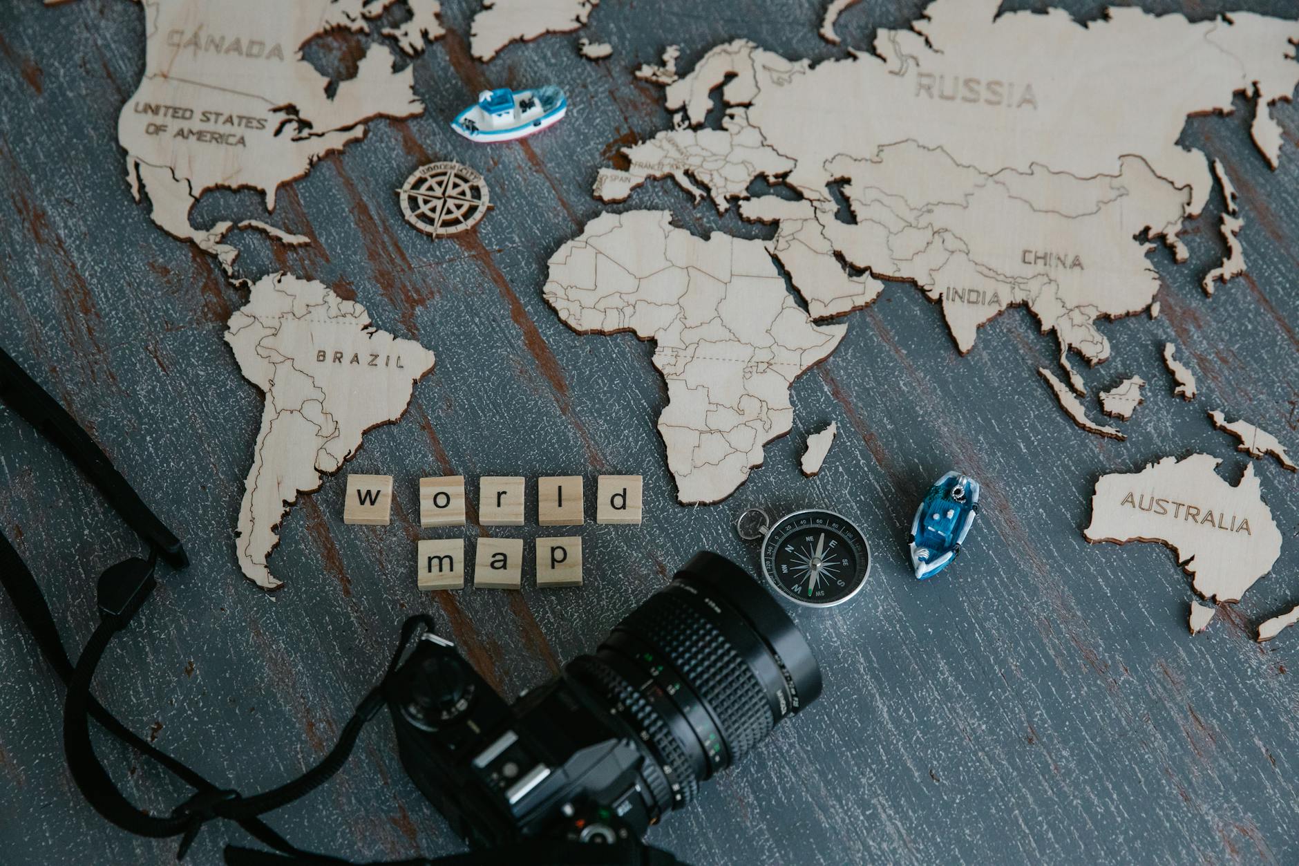 Drewniana mapa świata z kompasem i aparatem w ujęciu z góry