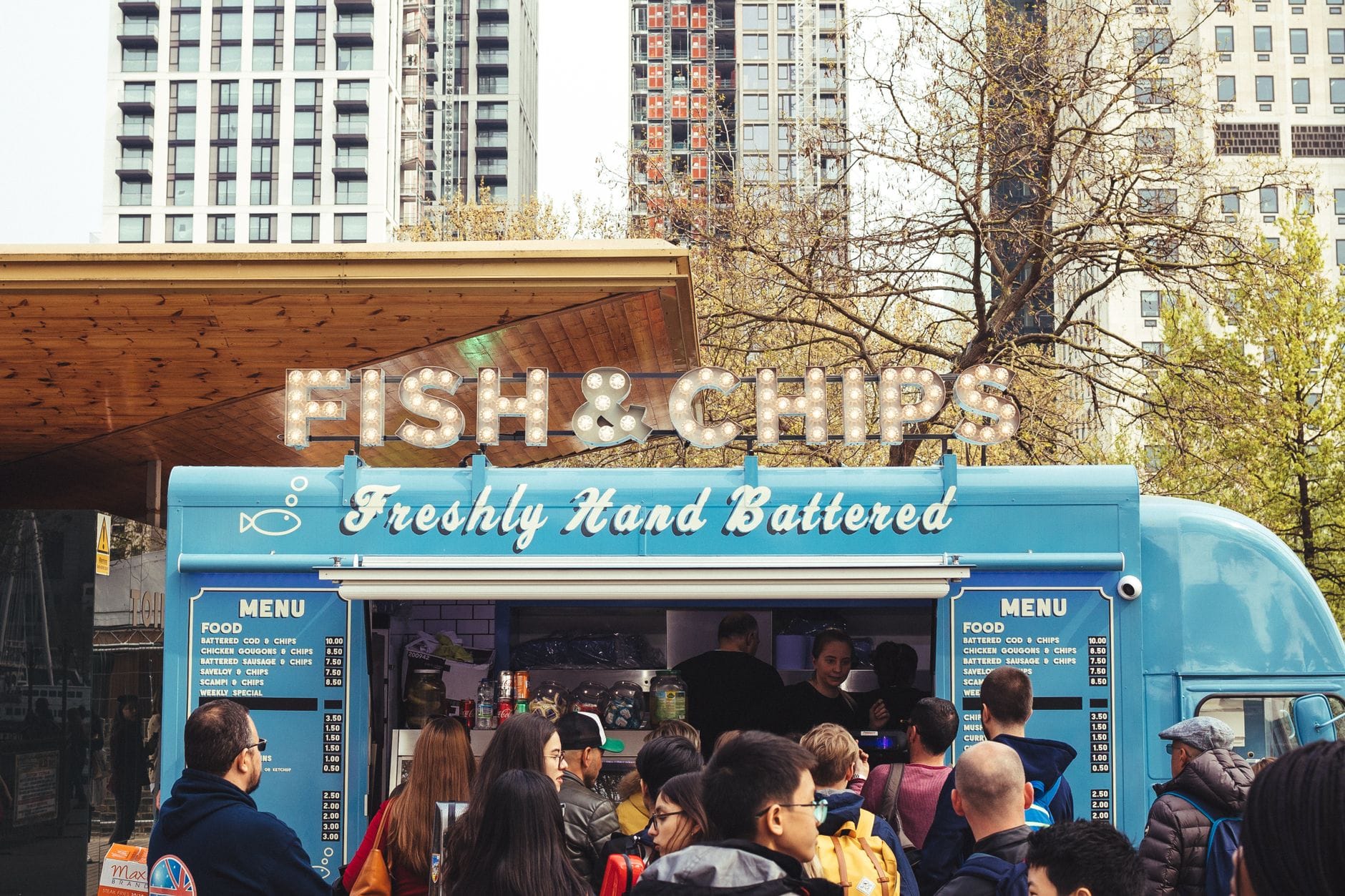 Jak jeść fish and chips jak miejscowi i nie wyjść na turystę Ludzie jedzą fish and chips przy food trucku w brytyjskim mieście