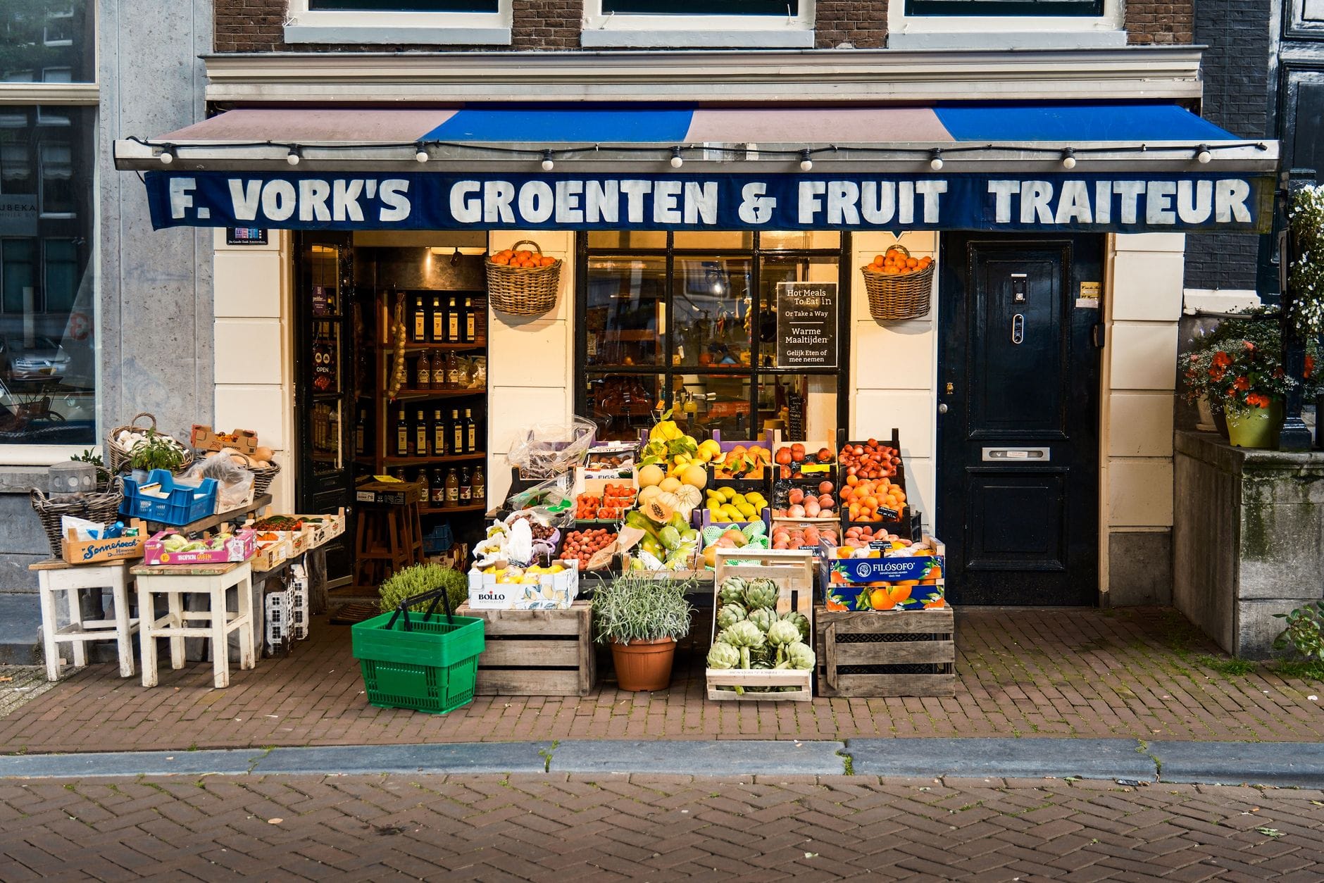 Stoisko z kolorowymi warzywami i owocami przed sklepem w Amsterdamie