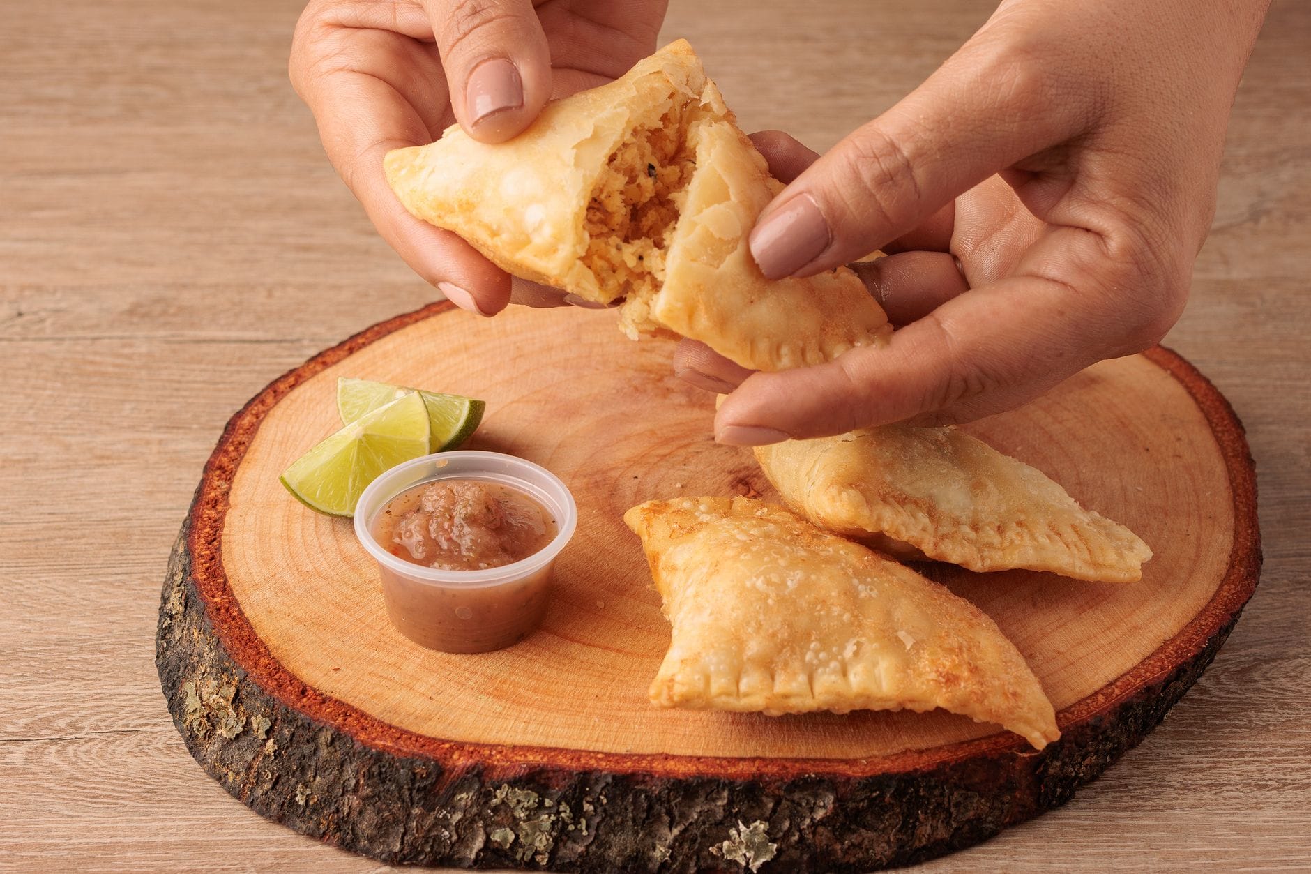 Kolumbijskie empanadas z pikantną salsą i limonką na desce