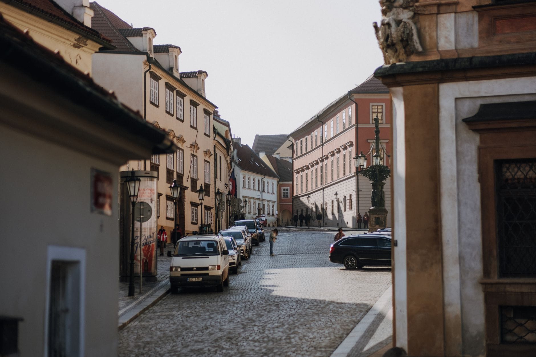 Słoneczna brukowana ulica w Czechach z zabytkowymi kamienicami i autami