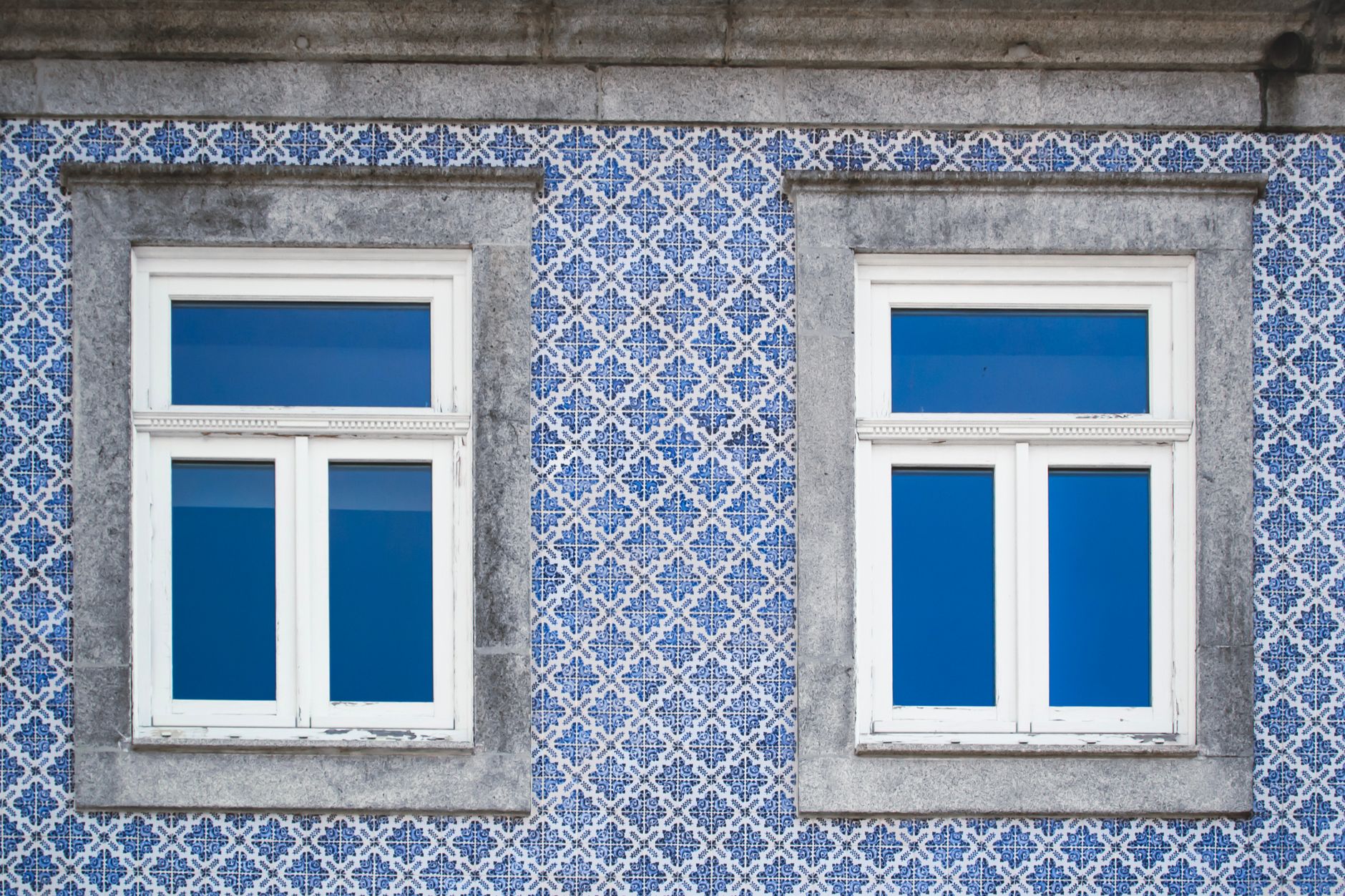 Zbliżenie fasady w Porto z niebieskimi azulejos i białymi oknami